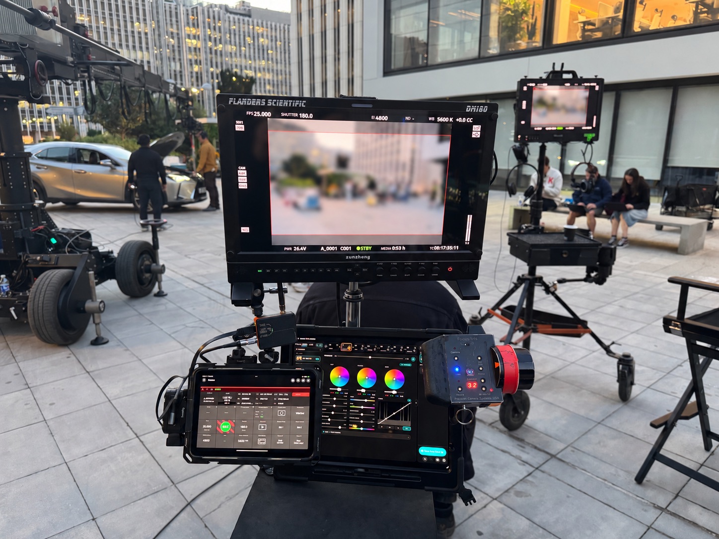 Dawn on an office plaza: a Flanders Scientific DM160 over two iPads, camera control on the left and GRADE on the right, with a Preston hand unit and a crane behind