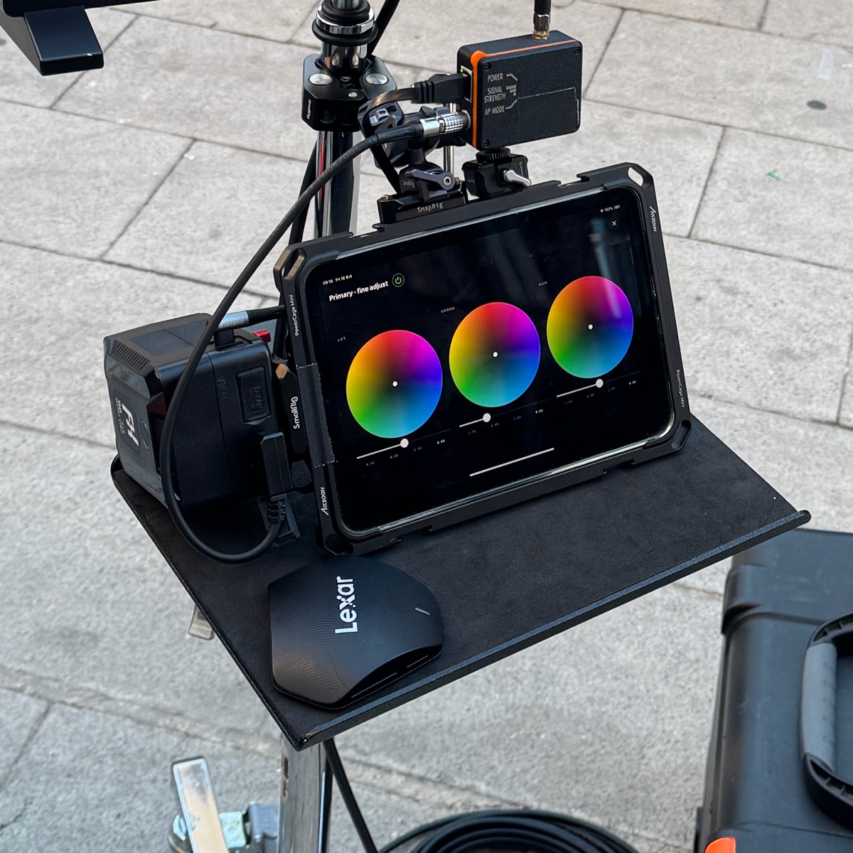 Close-up of the iPad on the stand tray running GRADE fine-adjust color wheels, with the wireless receiver above and a mouse beside it