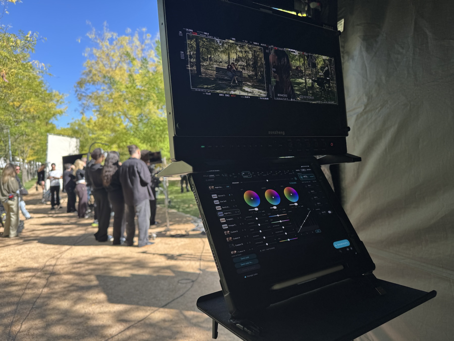GRADE on an iPad under a DM160 showing two camera feeds, on a stand in a DIT tent in a park
