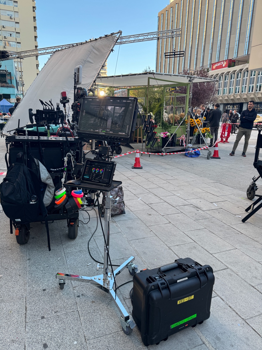 The whole DIT corner on a city square: camera cart with tape rolls, the DM160 and iPad on a stand, and the Pelican case on the ground