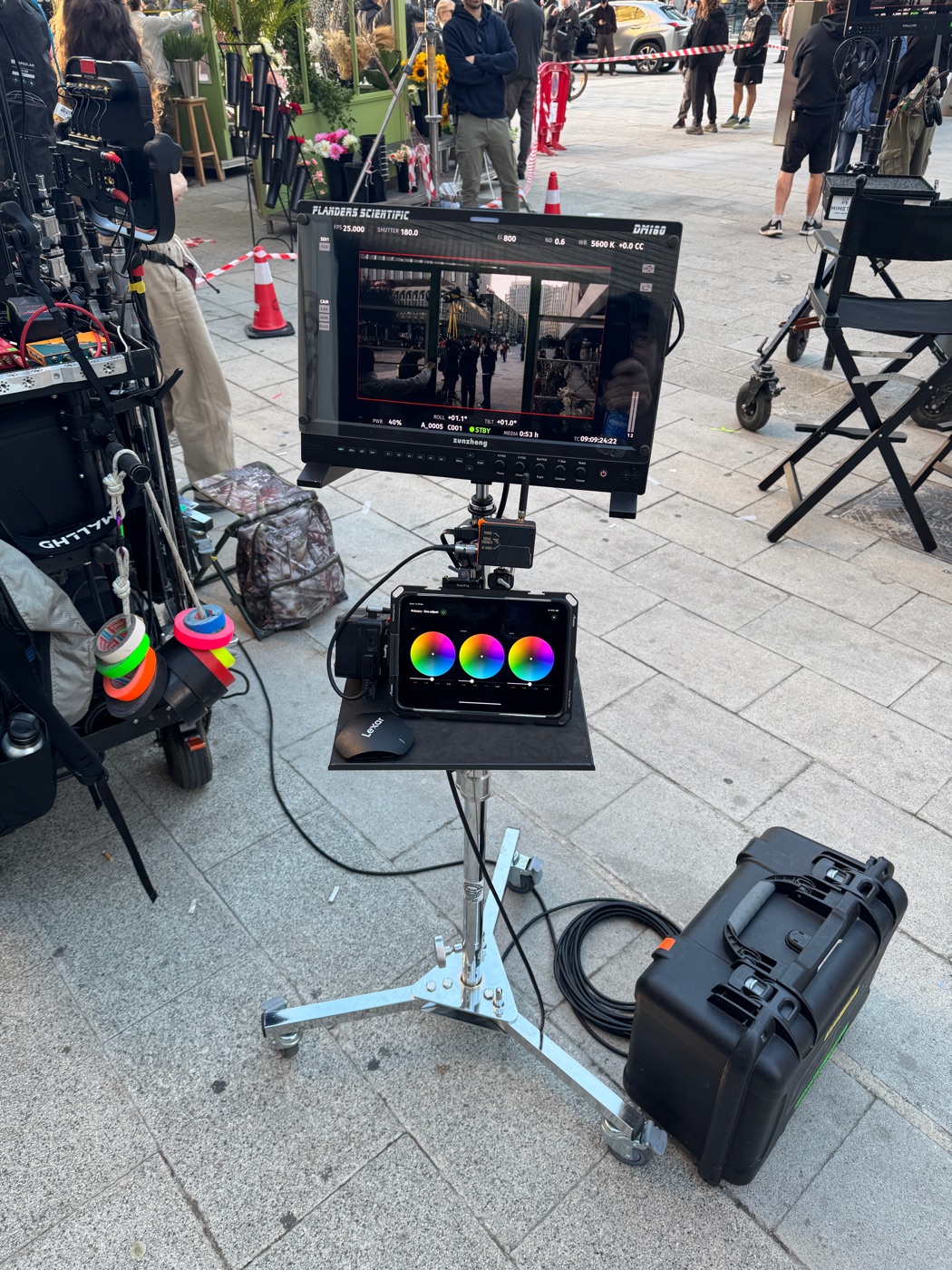 Morning on a city square: the DM160 over the iPad running GRADE color wheels, a mouse on the tray, the flight case and the camera cart beside the stand